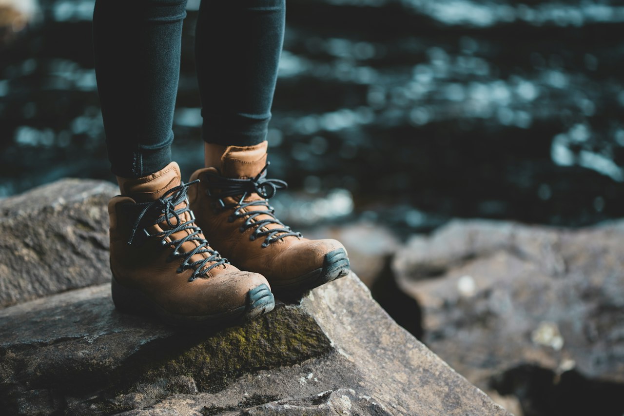 Walking boots planted on a mossy rock beside a river
